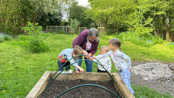 Family Planting Seeds In A Raised Planter Bed